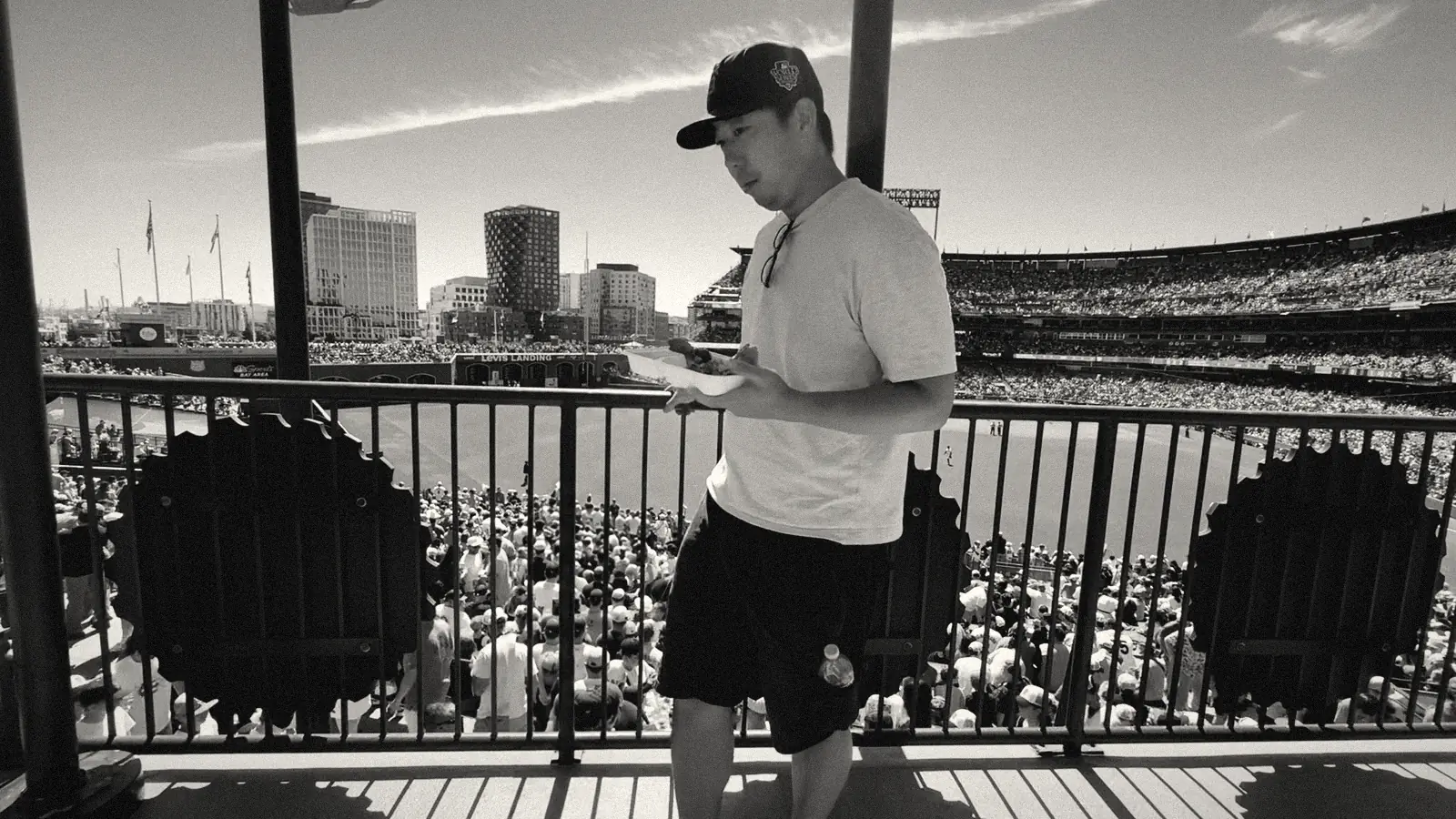Daniel at a Giants game, plate of food in hand, at the outfield railing